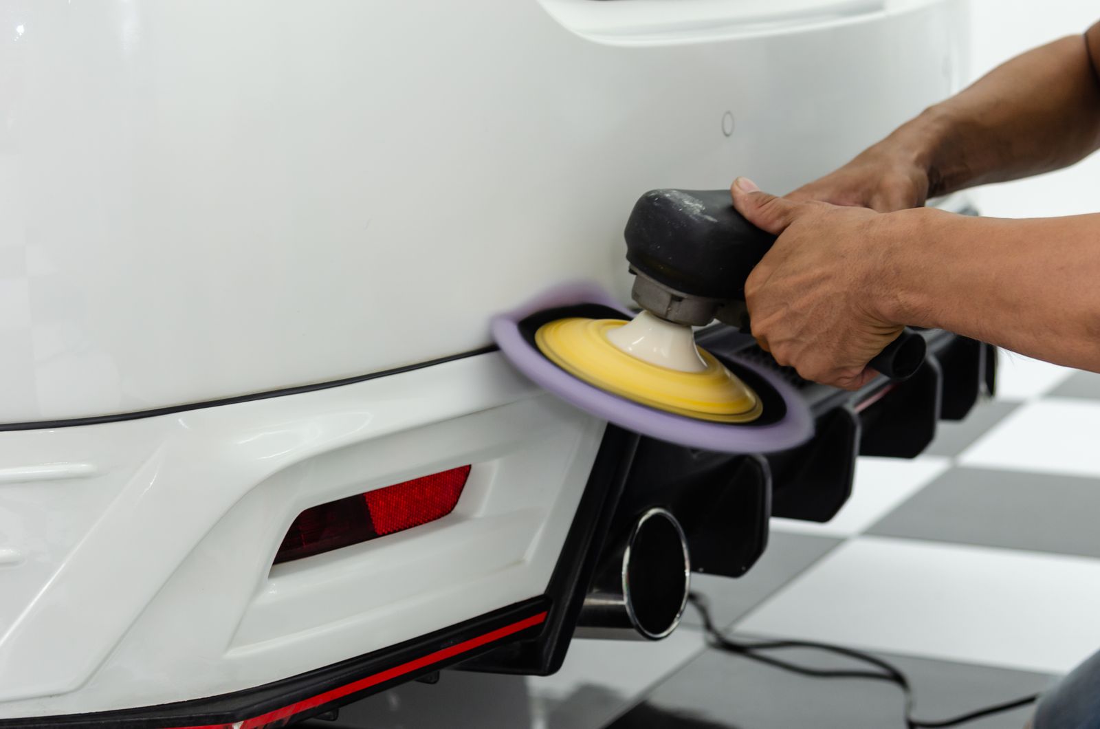 Paint correction close-up - detailer polishing a car with a power tool